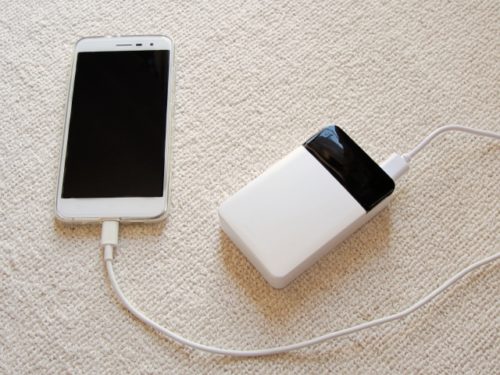 白いモバイルバッテリーとスマートフォンをケーブルでつないだ写真