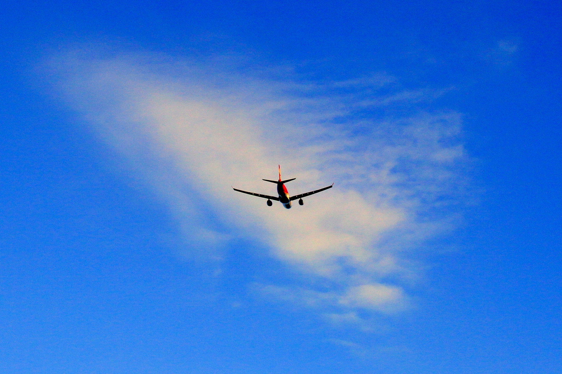 青空に浮かぶ雲と、遠くを飛ぶ小さな旅客機