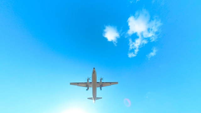 青空を見上げたところに小さく飛ぶ旅客機