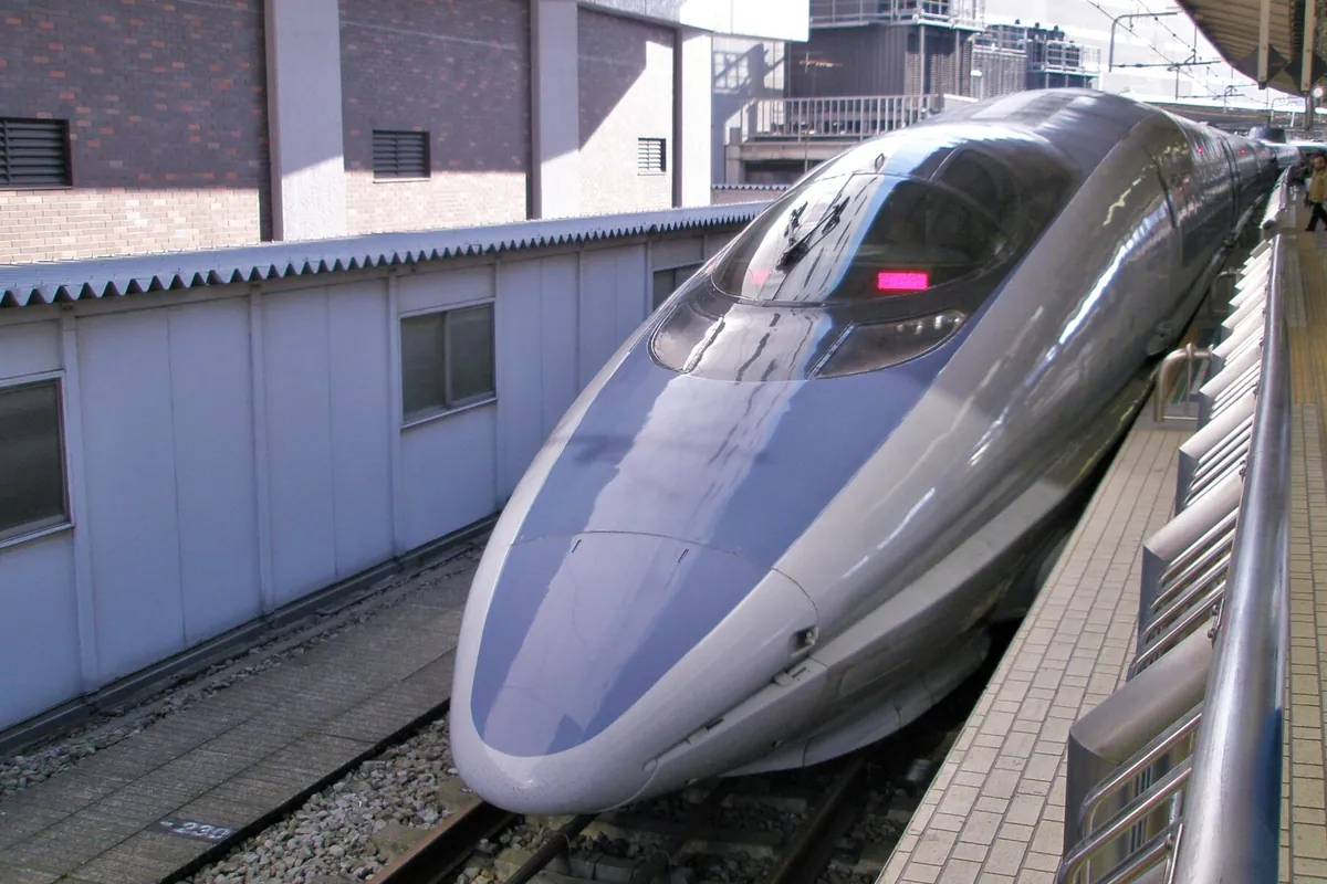ホームに停車する500系新幹線車両の青い流線形の先頭部分を正面から見た写真