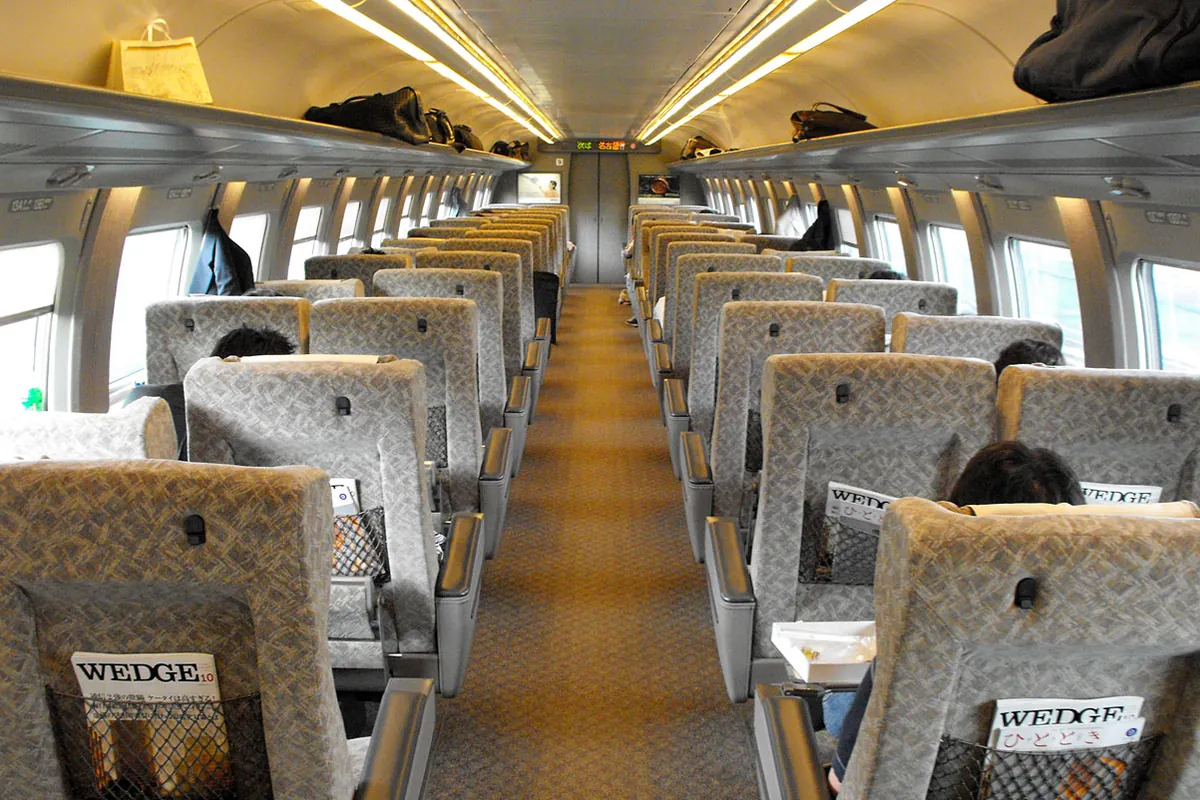 新幹線の車内で灰色の座席が左右2列ずつ並び、座席背面にWEDGEなどの雑誌が収められている様子の写真
