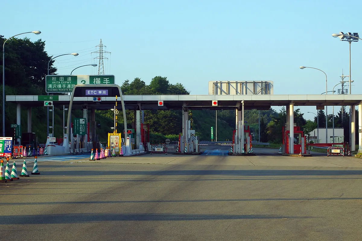 秋田自動車道の横手IC料金所で、ETC専用レーンと一般レーンが並び「横手」の案内標識が掲げられている様子の写真