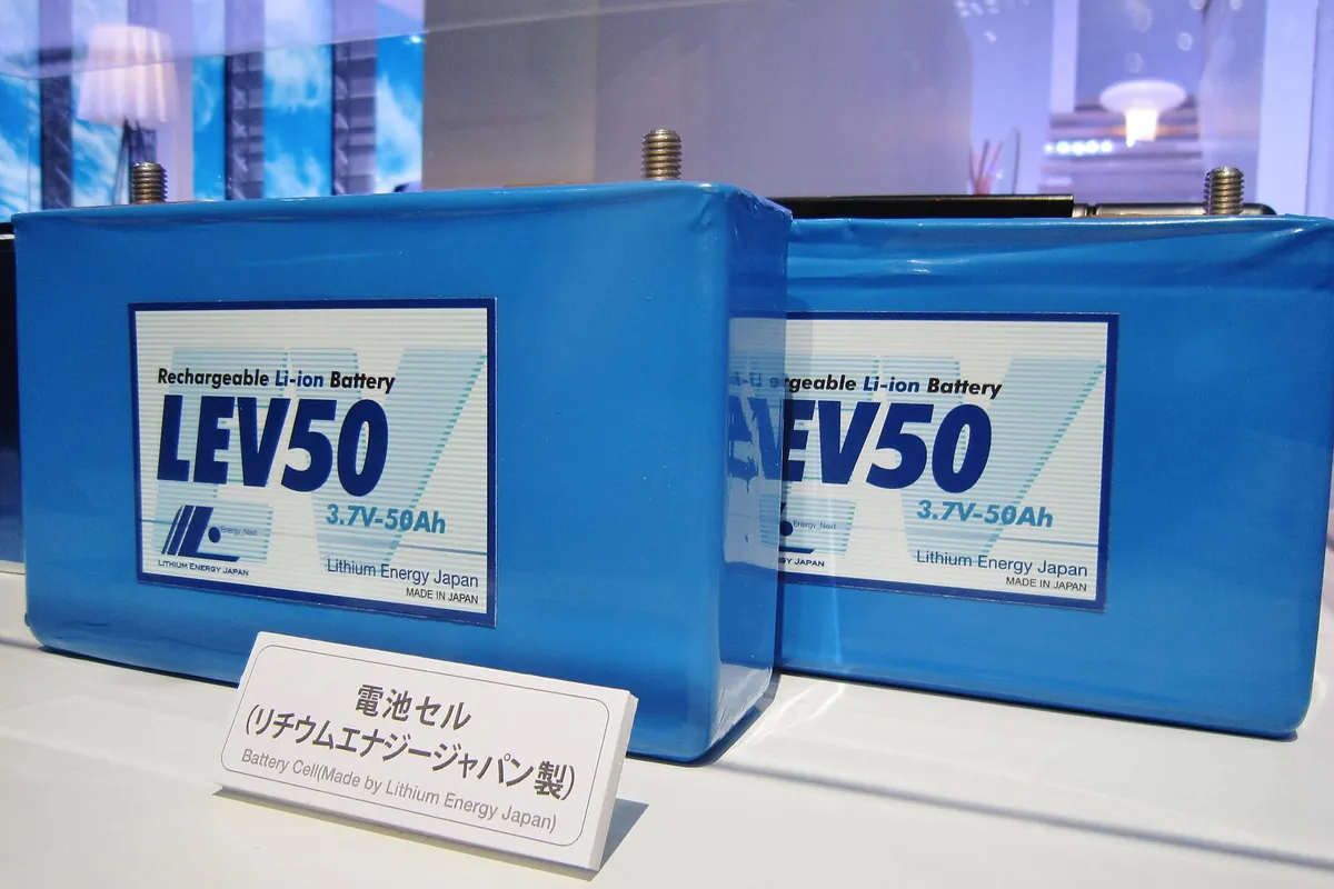 「LEV50 Rechargeable Li-ion Battery」と表示されたリチウムイオン電池セルが2個並び、手前に「電池セル(リチウムエナジージャパン製)」の説明カードが置かれている写真