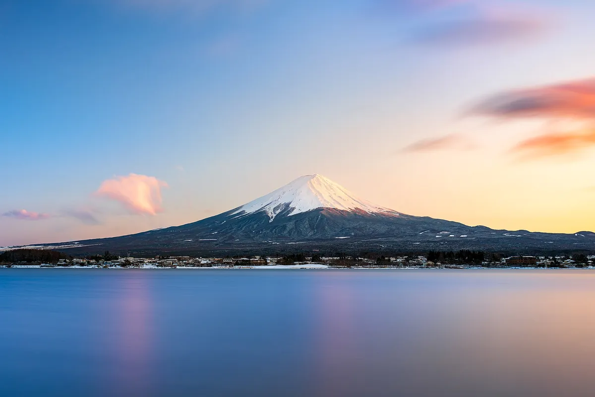 湖の対岸に雪をかぶった富士山がそびえ、水面に山の姿が映り込んでいる景色の写真