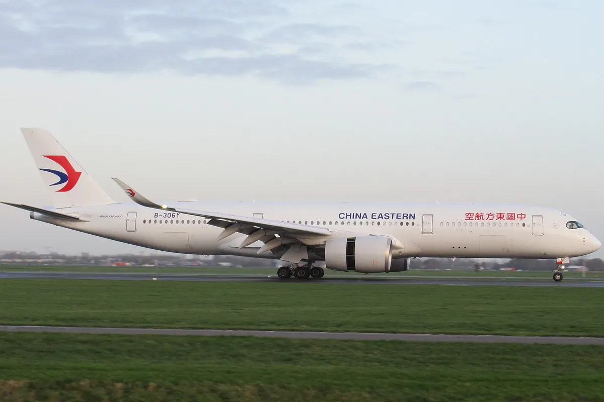滑走路脇の芝生を背景に、中国東方航空のエアバス機が垂直尾翼の赤青ロゴと「空航方東国中」の文字を見せて走行する様子の写真