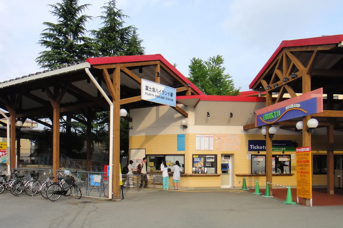 「富士急ハイランド駅」の看板がある富士急行線の駅舎とチケット売り場の様子の写真