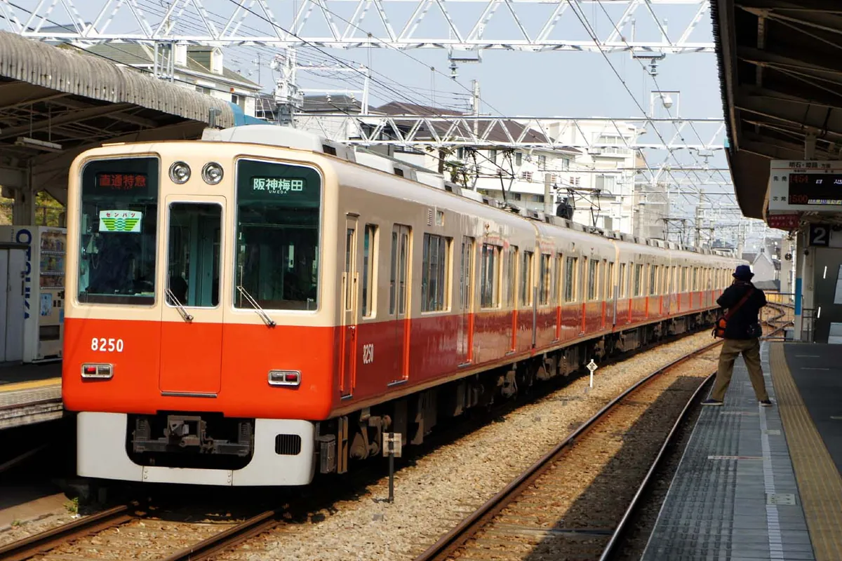 阪神電車の赤とベージュの車両が「阪神梅田」行きの表示でホームに停車している様子の写真