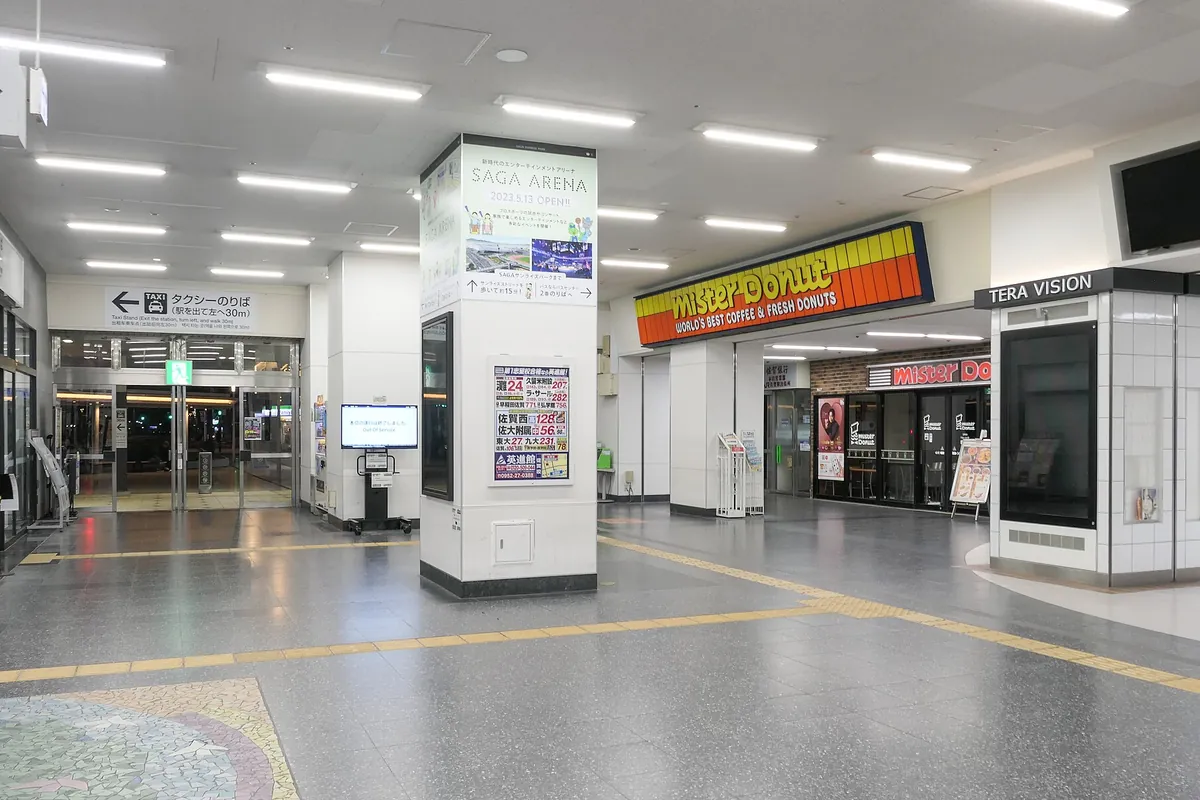 JR佐賀駅のコンコースで、タクシーのりば案内板とミスタードーナツの店舗が並ぶ様子の写真