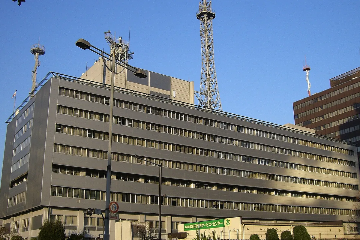 高層ビルの屋上に鉄塔やアンテナが並び、1階に「政府刊行物サービスセンター」の看板が掲げられた庁舎の写真