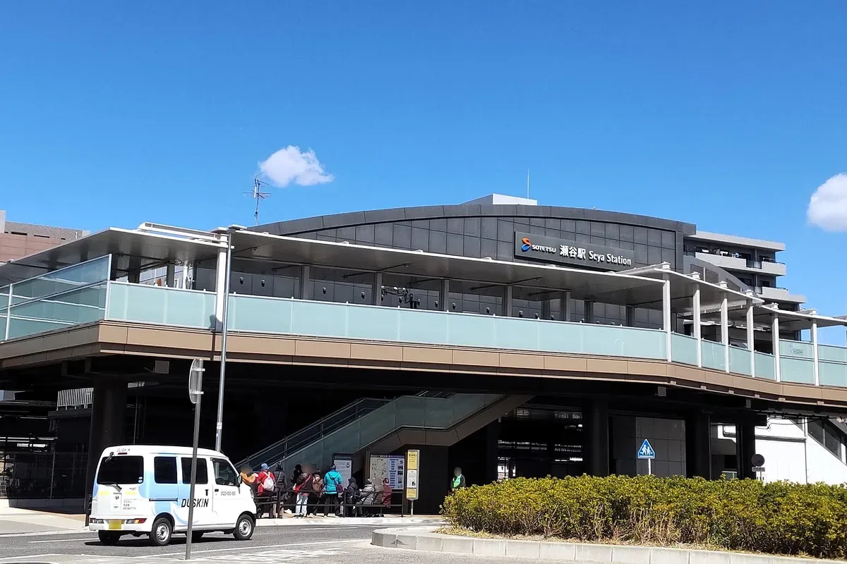 相鉄本線の瀬谷駅の駅舎と、駅前のベンチで人が待っている様子の写真
