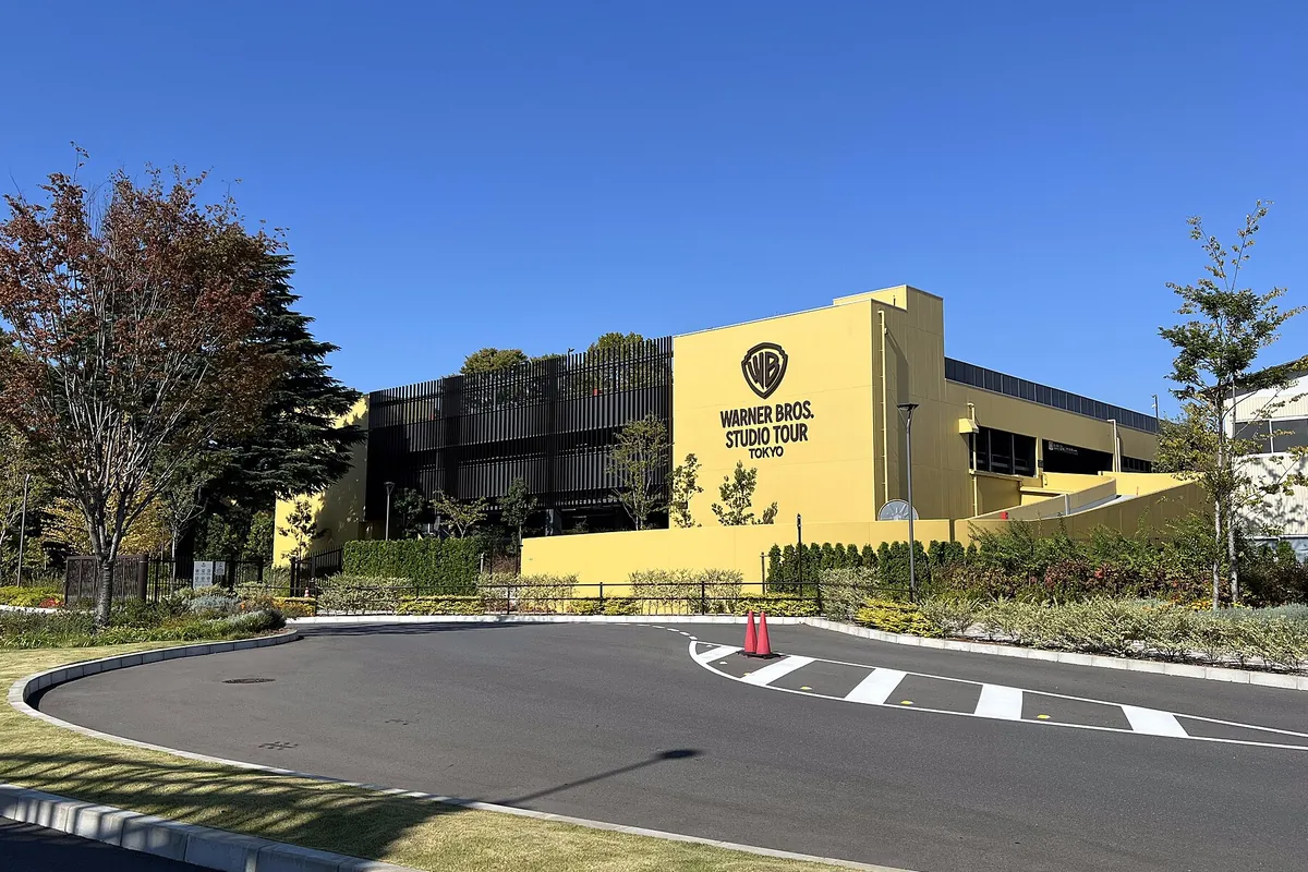 ワーナー ブラザース スタジオツアー東京の黄色い外壁の建物に「WARNER BROS. STUDIO TOUR TOKYO」のロゴが掲げられている様子の写真