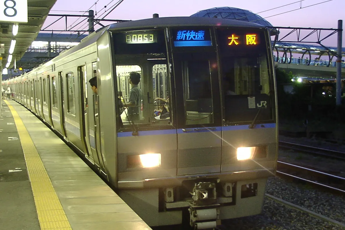 JR新快速電車の先頭車両が夜のホームに停車し、前面に「新快速 大阪」の表示が出ている写真