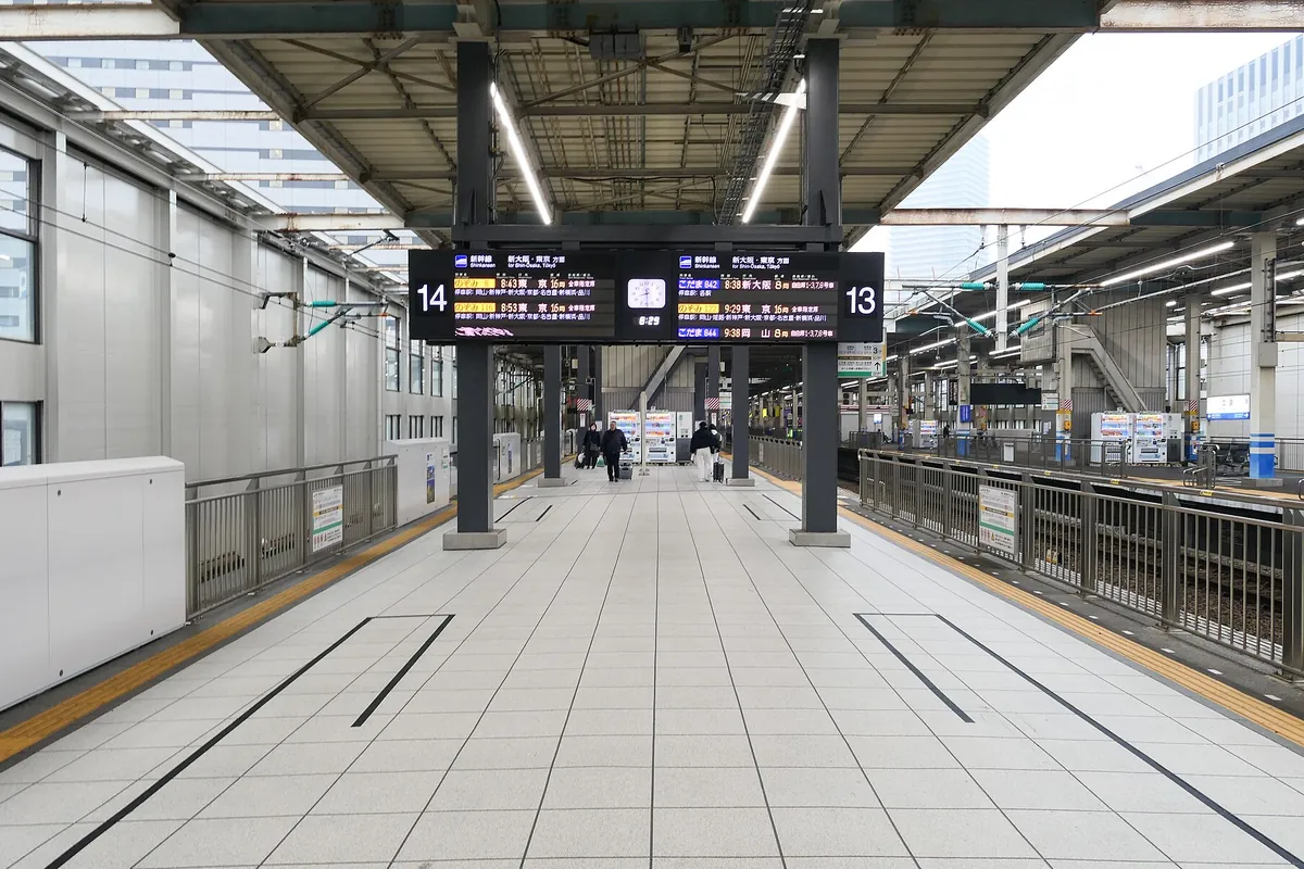 新幹線ホームで「13」「14」の番線表示と発車標が見える、屋根付きホームの様子の写真