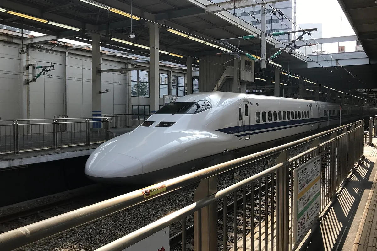 ホームに停車する白色の新幹線車両の先頭部分を正面寄りから撮った写真