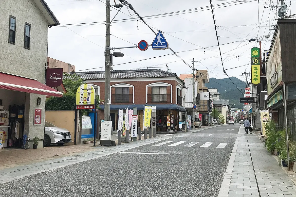 商店や旅館が並ぶ温泉街の通りに、案内の幟や看板が立ち並ぶ様子の写真