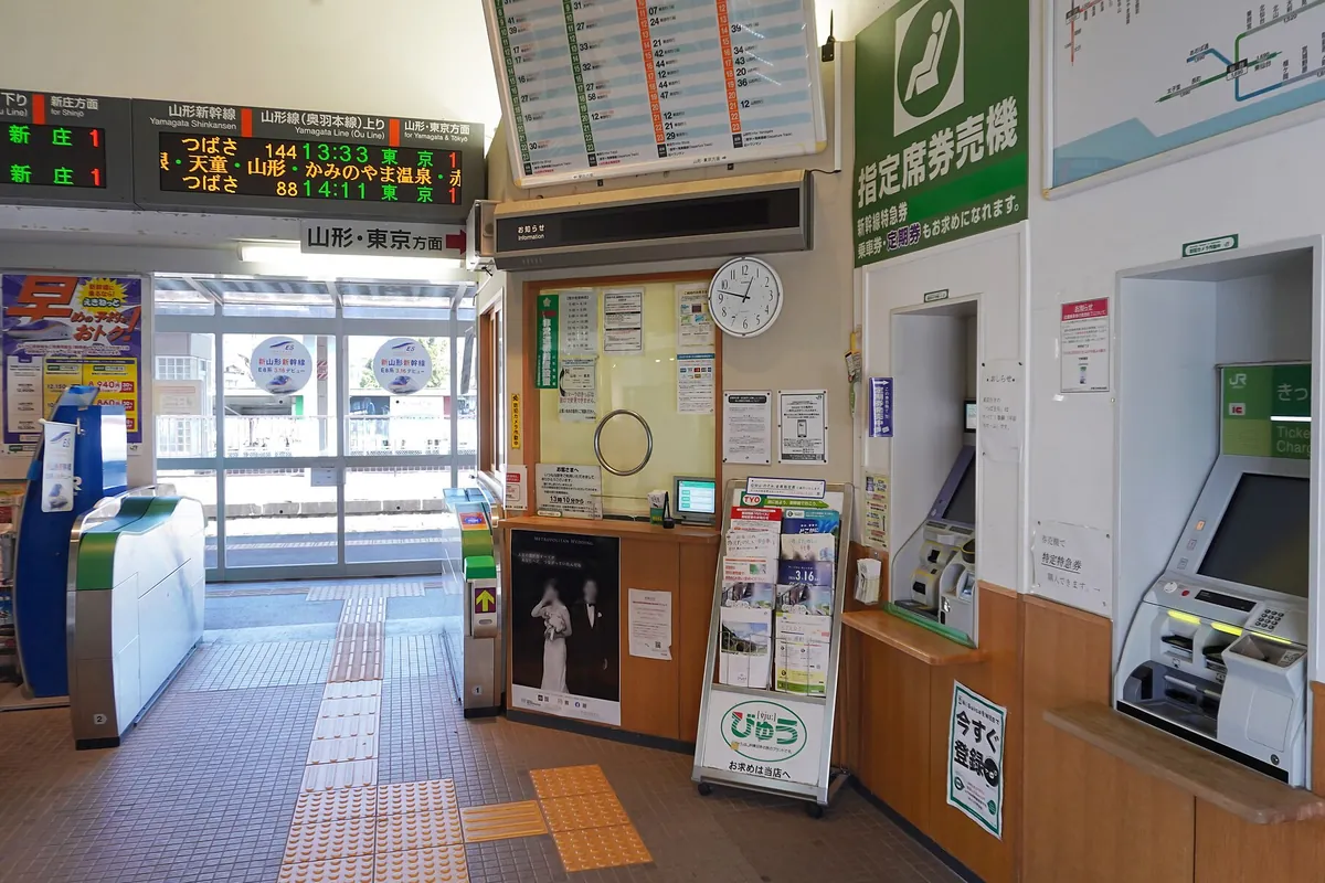 JR東日本の駅構内で自動改札機と指定席券売機、発車標が並ぶ改札口付近の様子の写真