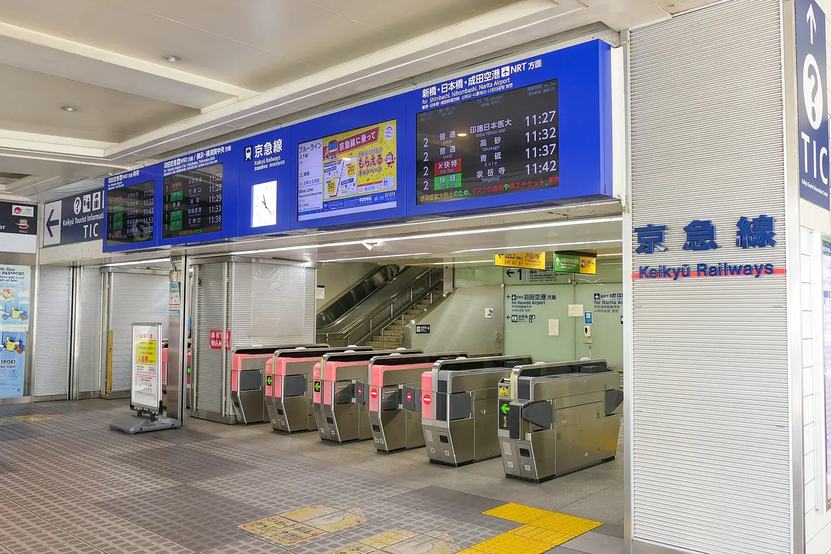 京急電鉄の駅の改札口で「京急線 Keikyū Railways」の表示とピンク色の自動改札機が並ぶ様子の写真