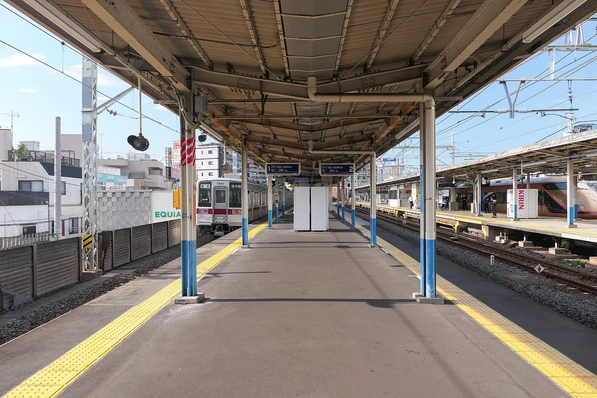 東武鉄道の駅のホームで屋根付きの通路越しに東武の電車とオレンジ色の特急車両が停まる様子の写真