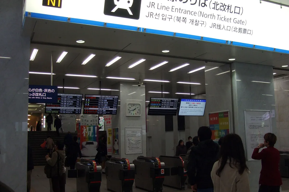 駅構内の「JR Line Entrance(North Ticket Gate)」と書かれた改札口に案内表示や乗客が並ぶ様子の写真