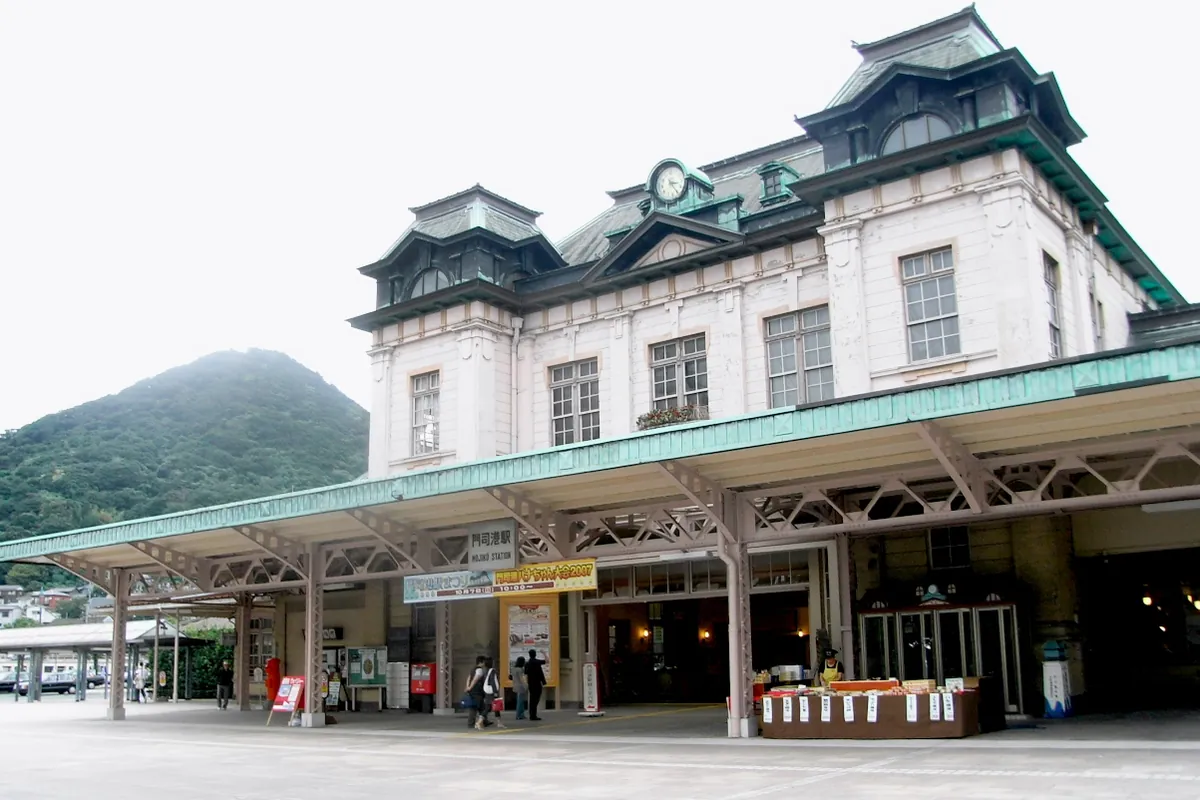 「門司港駅」の駅名標がある洋風の駅舎とその正面広場の様子の写真