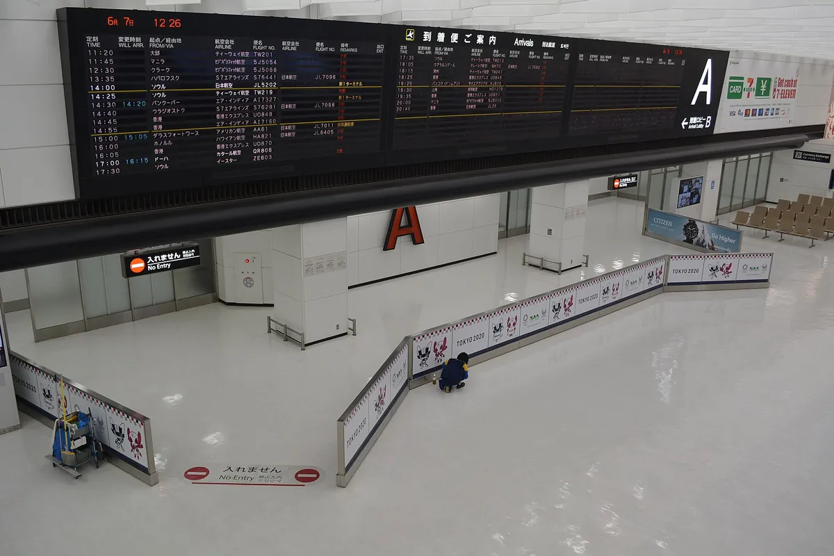成田空港の到着ロビーで、到着便案内の電光掲示板と「No Entry」のサインが並ぶ様子の写真