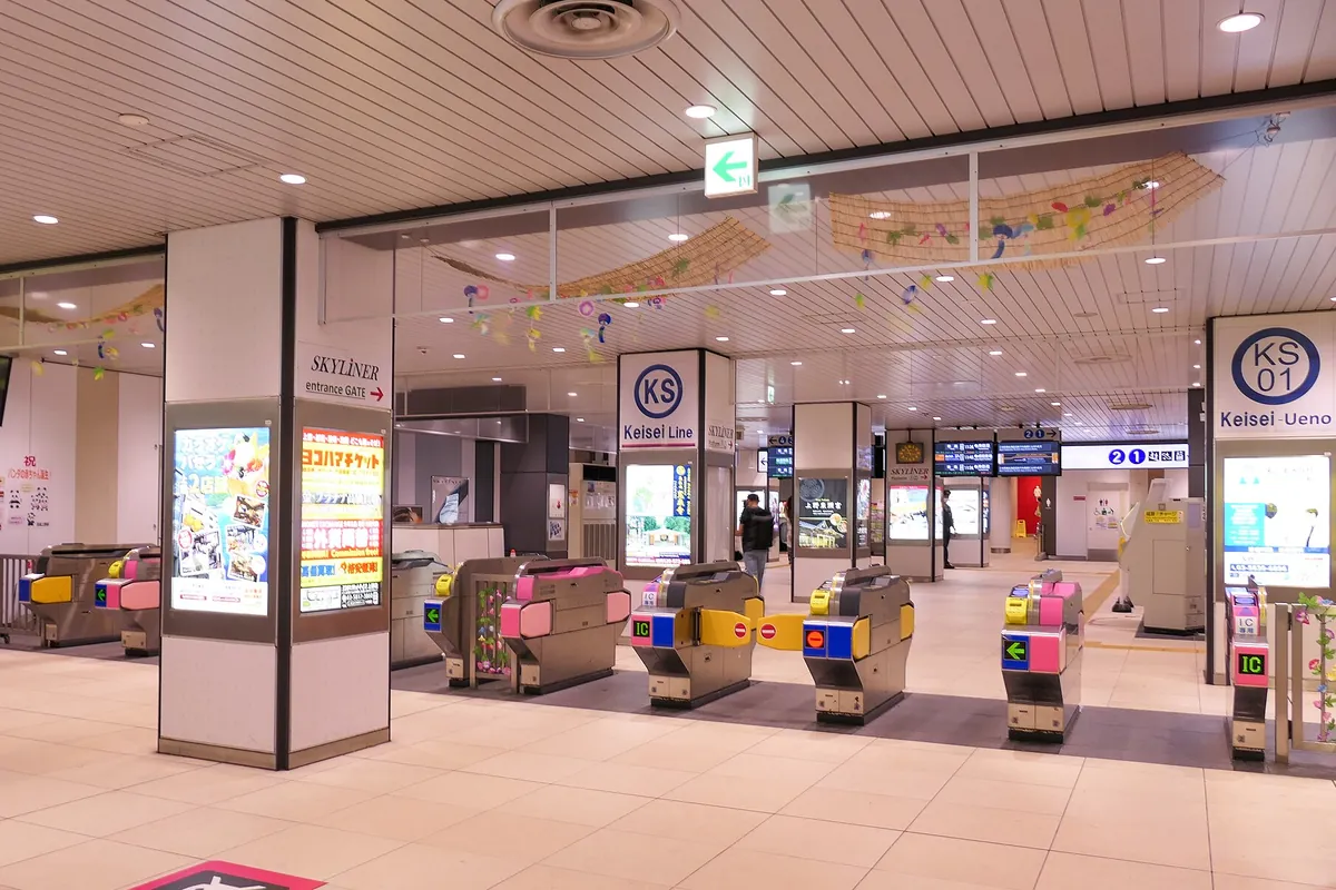 「Keisei-Ueno」と表示された京成上野駅の改札口で、ICカード対応の自動改札機が並ぶ様子の写真