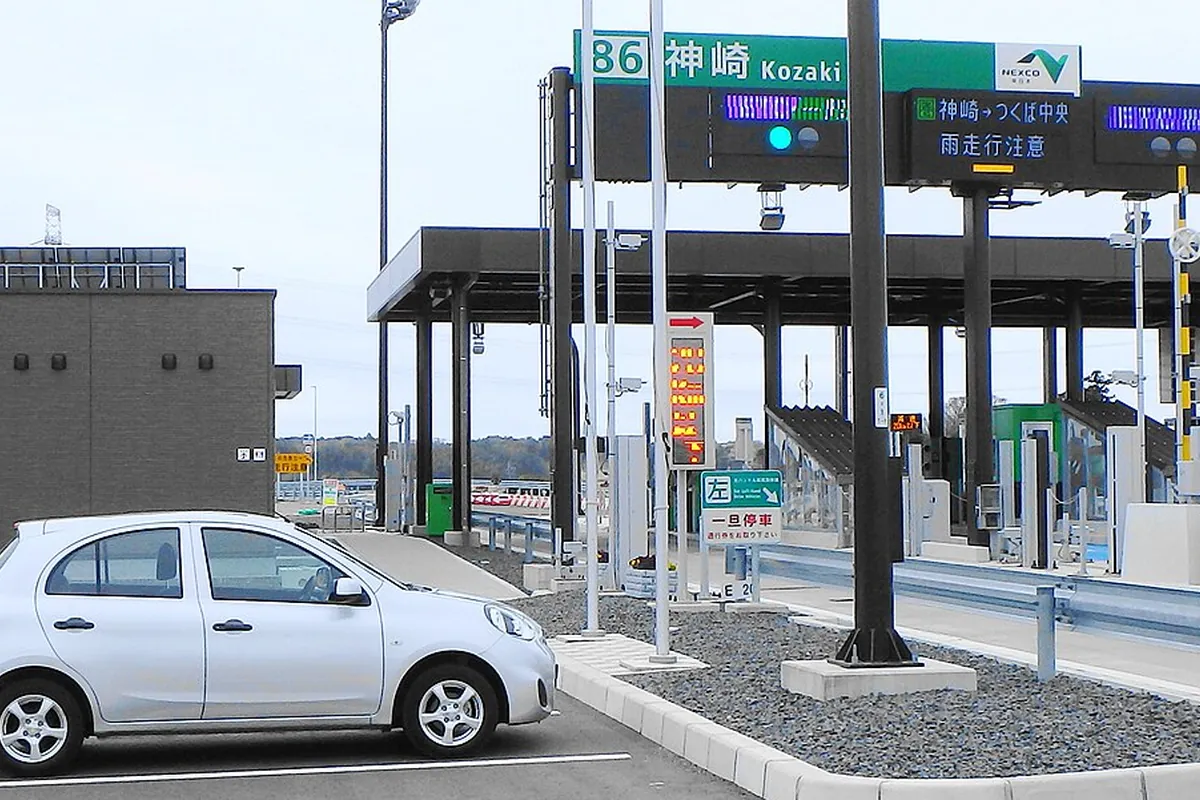 圏央道神崎ICの料金所で「86 神崎 Kozaki」の標識とつくば中央方面の案内表示が掲げられている様子の写真