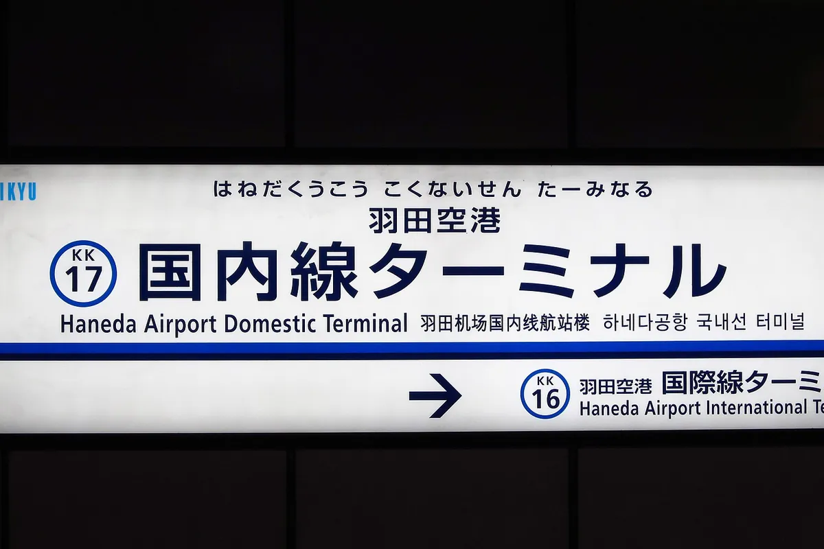 「羽田空港 国内線ターミナル」と書かれた京急の駅の案内板で、国際線ターミナル方面への矢印も示された写真