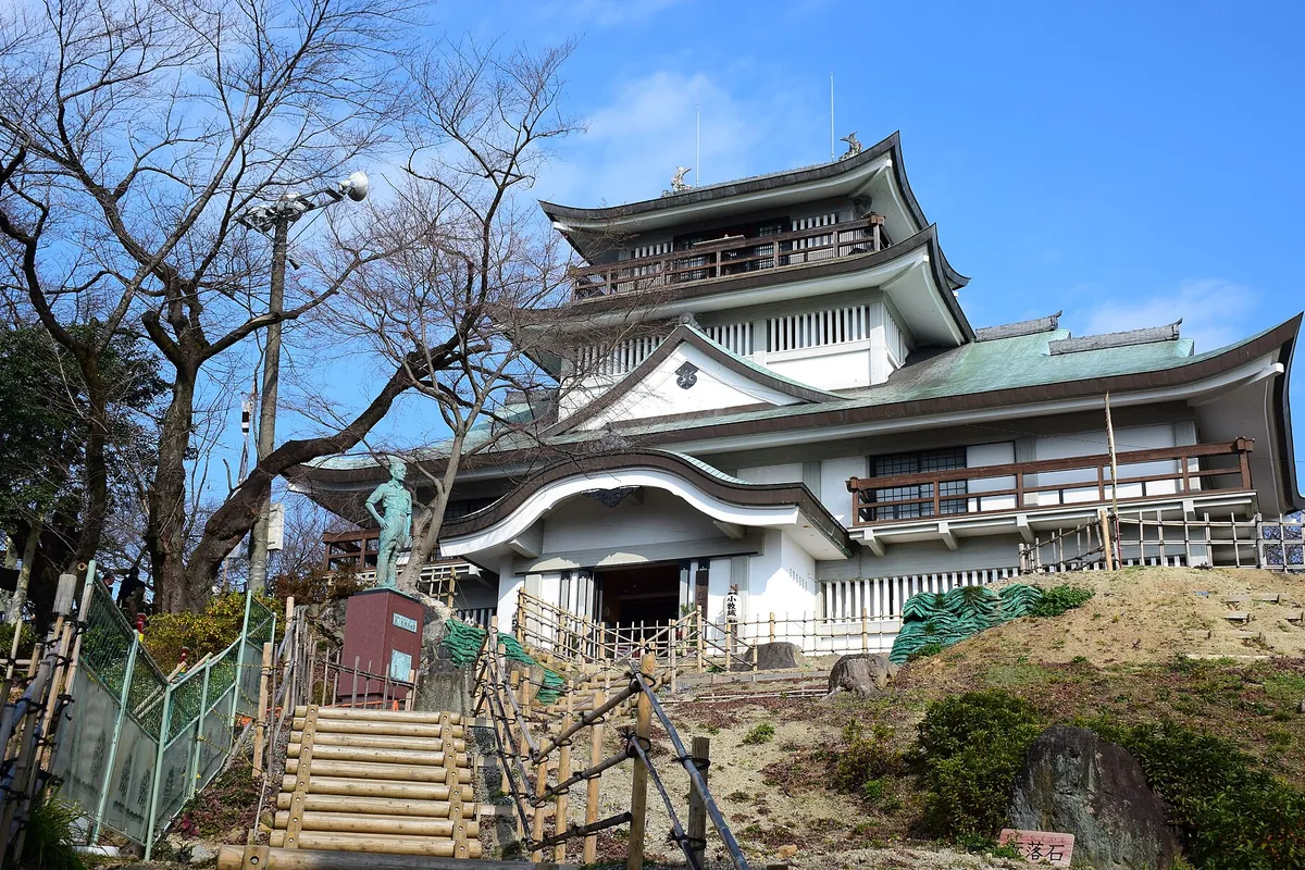 小牧山の山頂に建つ小牧山城の天守閣を見上げた外観と、入口前の石段や銅像の様子の写真