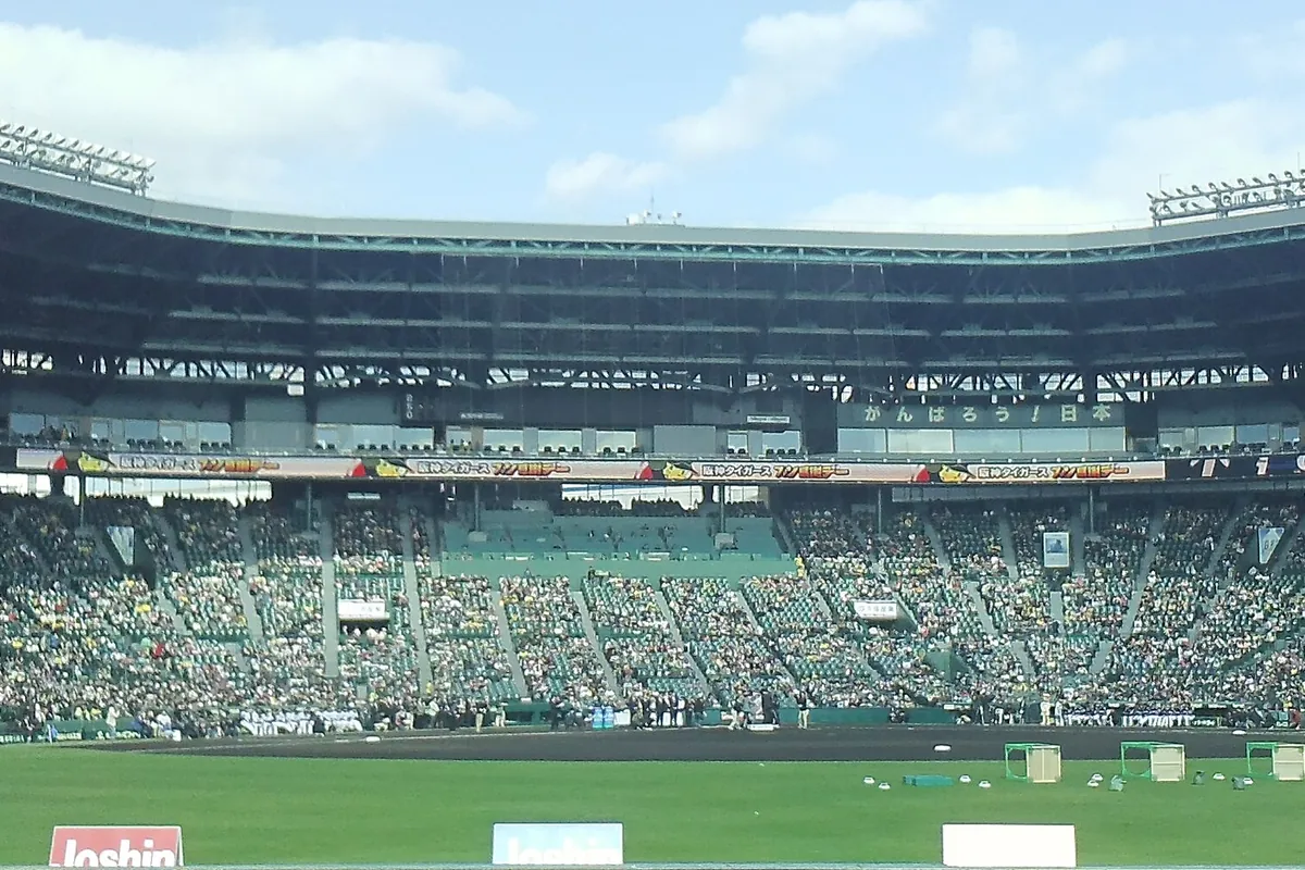 甲子園球場の内野スタンドから見た観客で埋まったスタンドとグラウンド、スコアボード付近の様子が写る写真