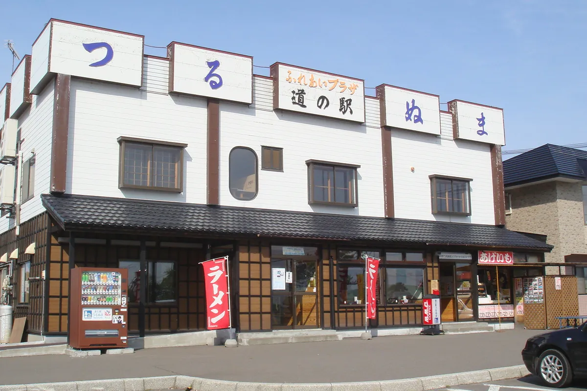 道の駅つるぬまの建物の外観で、「道の駅」「ふれあいプラザ」の看板と赤いのぼりが並ぶ様子の写真
