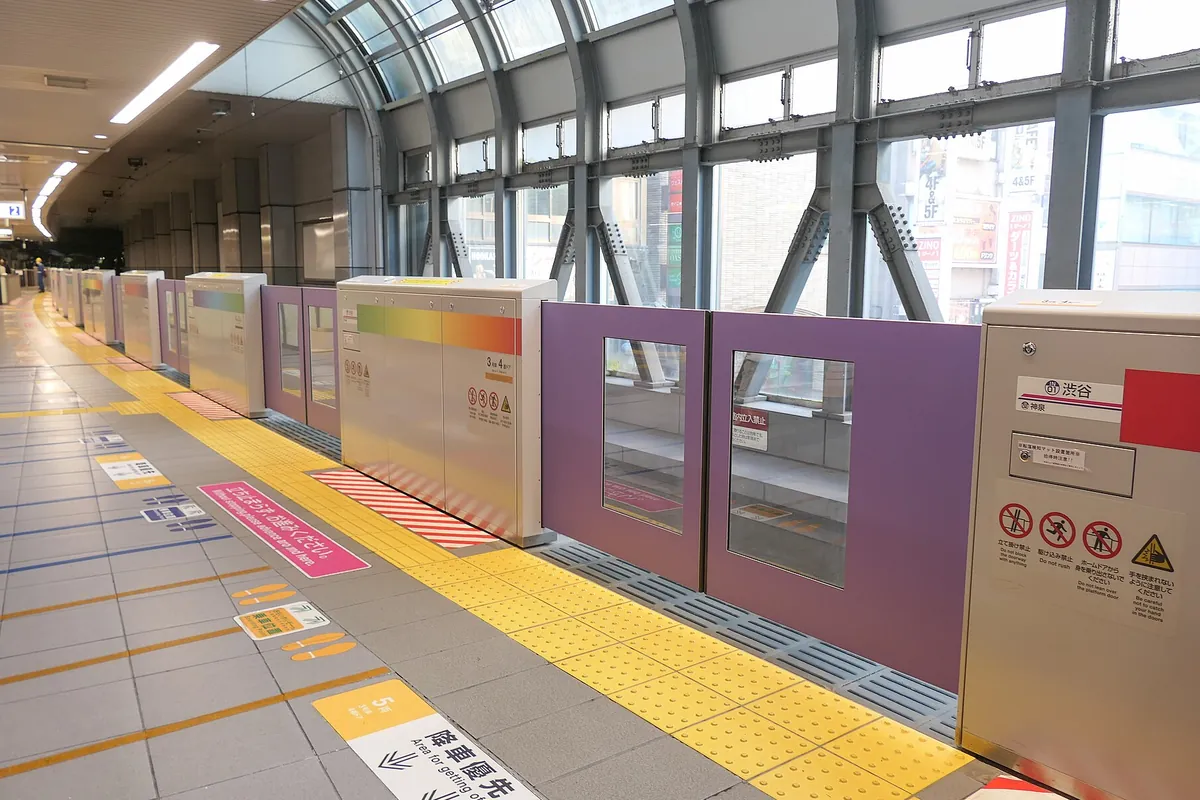ホームドアに「渋谷」の駅名標があり、紫色のホームドアが並ぶ駅ホームの写真