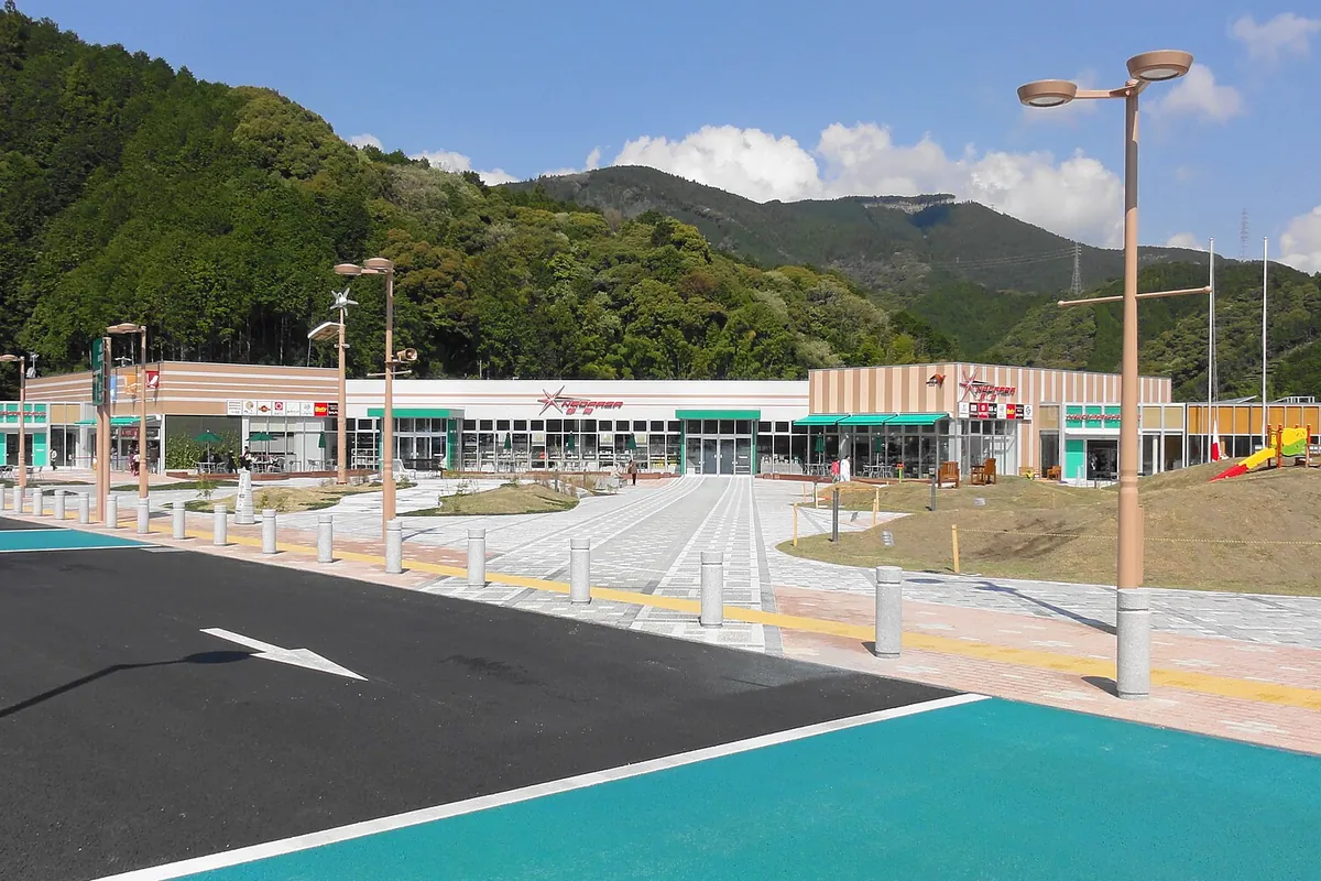 新東名高速道路のサービスエリアで、山を背景に商業施設の建物と広場が広がる様子の写真