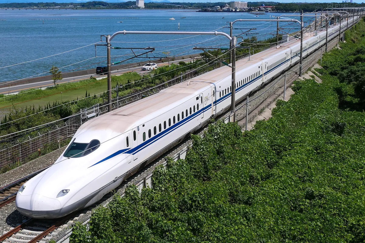 東海道新幹線の新幹線車両が海沿いの線路を走行している様子の写真
