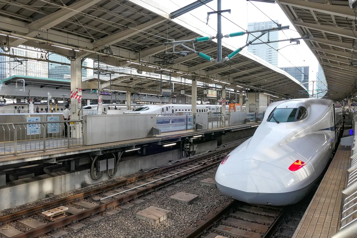 新幹線の駅のホームに先頭車両が停車し、奥に別の新幹線も並ぶ様子の写真
