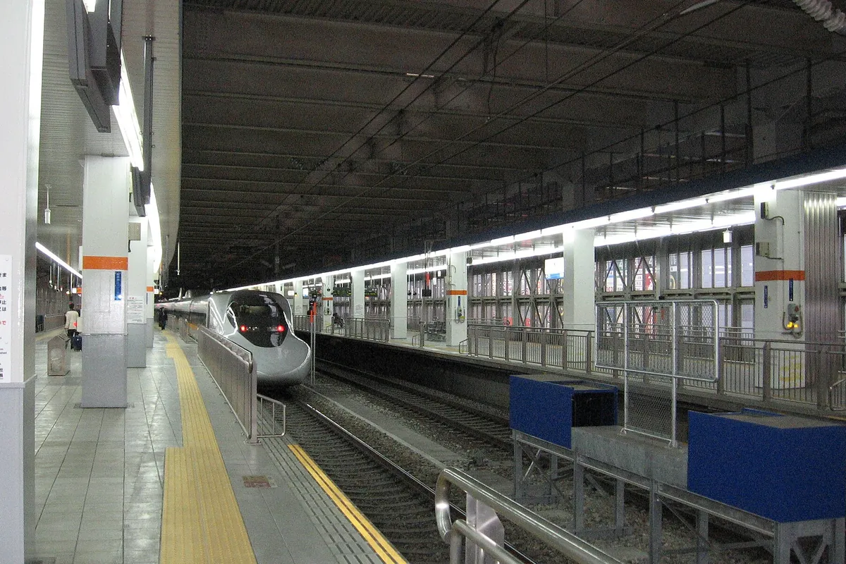 屋根のある新幹線の駅のホームに新幹線車両が入線してくる様子の写真