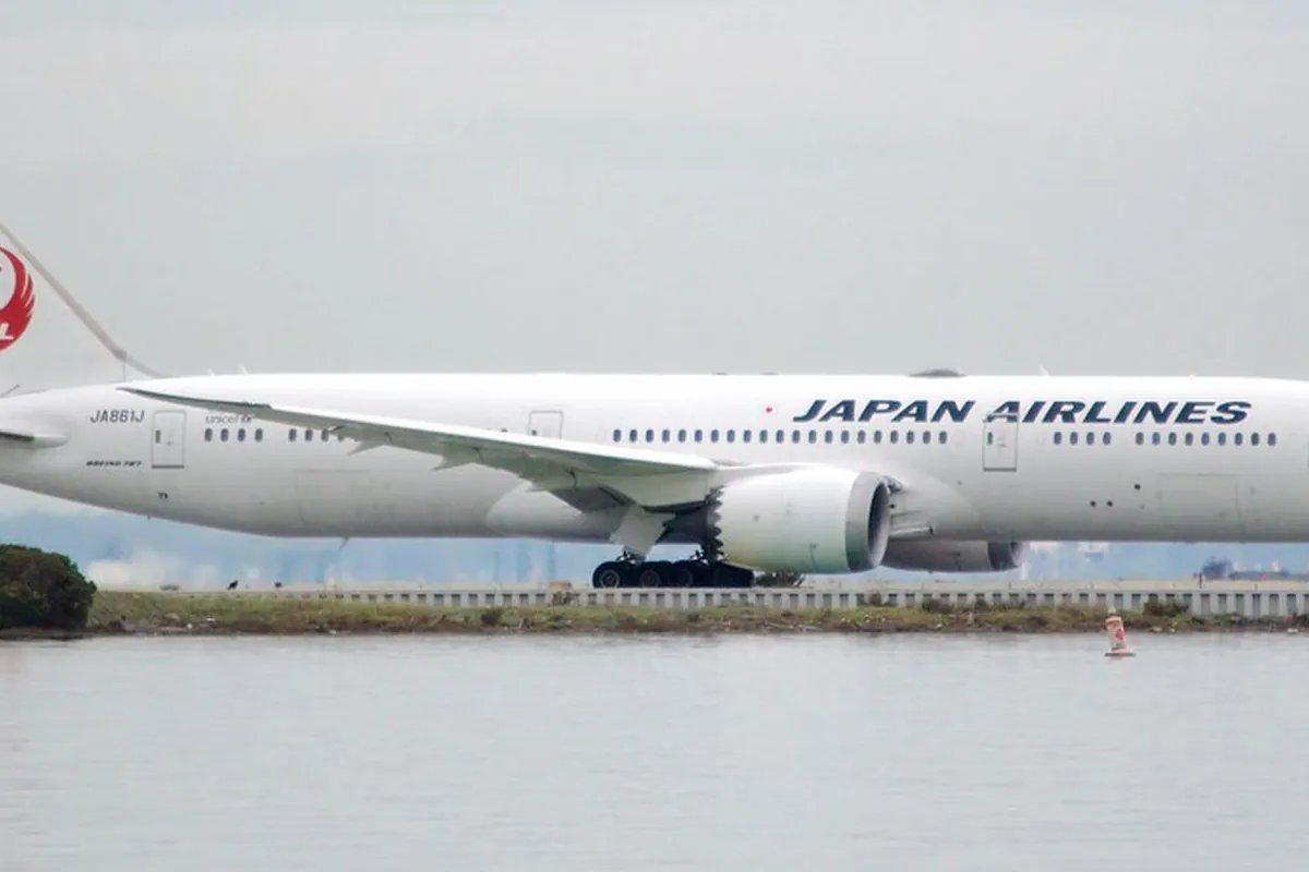 水辺の滑走路脇を走行する「JAPAN AIRLINES」と書かれた日本航空の旅客機の写真