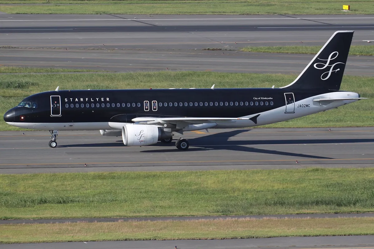 滑走路を走行するスターフライヤーの黒い機体のエアバスA320型機で「STARFLYER」の文字と登録記号JA02MCが見える写真