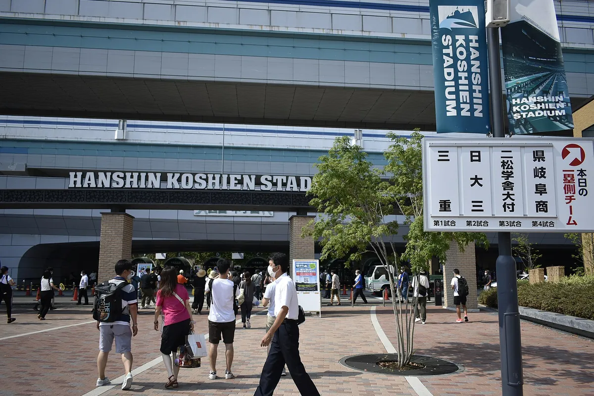 阪神甲子園球場の正面入口で「HANSHIN KOSHIEN STADIUM」の看板や対戦カードの掲示板が見える様子の写真