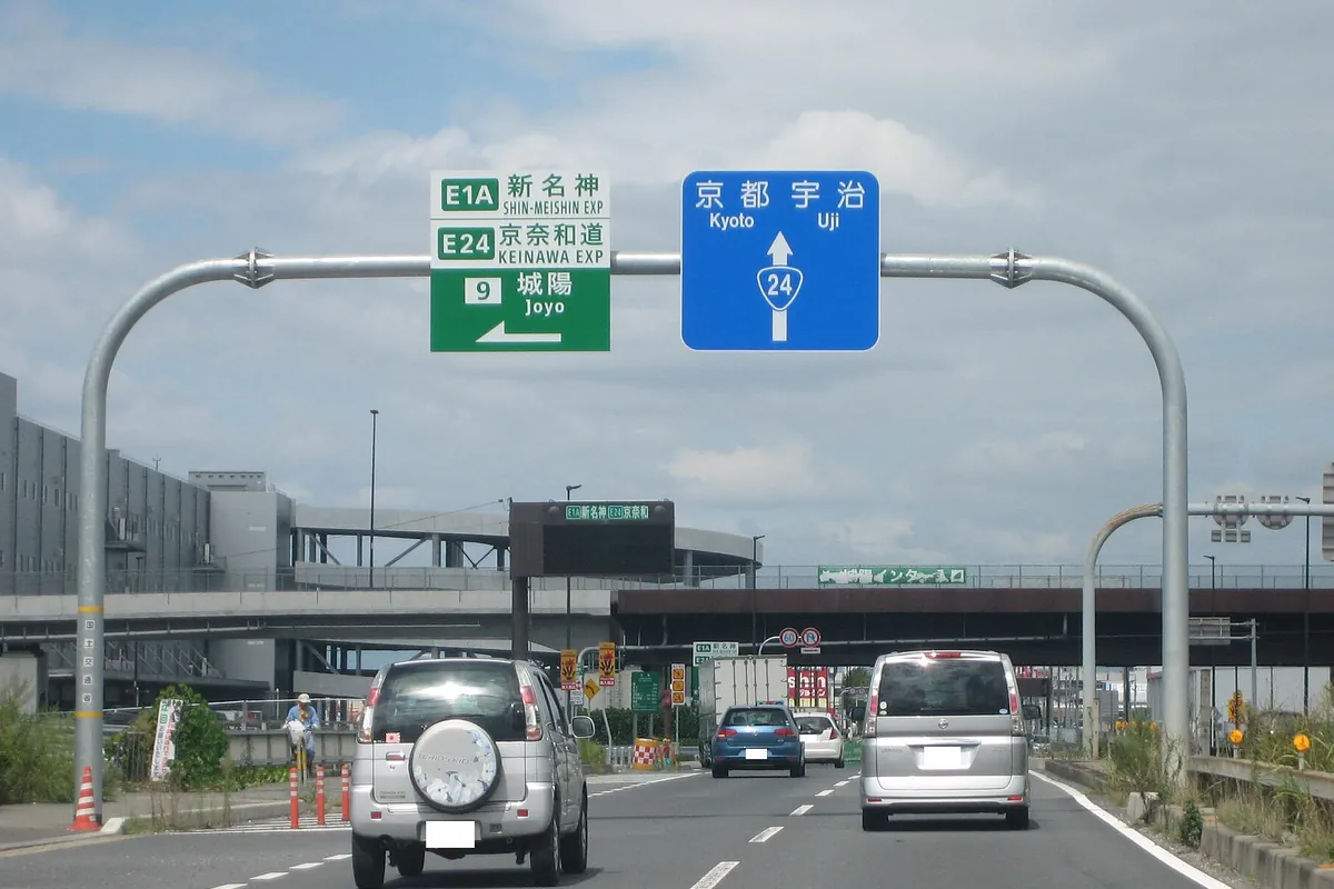 新名神高速道路「城陽」出口と国道24号京都・宇治方面を示す案内標識が並ぶ交差点の写真