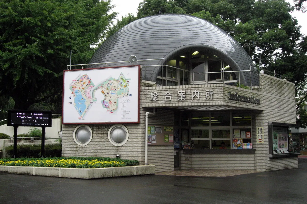 動物園の「総合案内所」と書かれたドーム型の建物と園内マップの看板が並ぶ入口付近の写真
