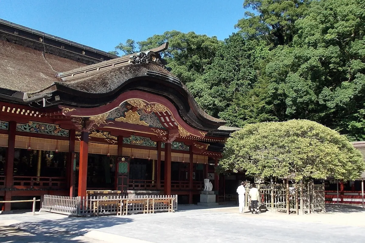 太宰府天満宮の本殿で、朱塗りの建物に茅葺き屋根と彫刻が施された装飾が写る写真