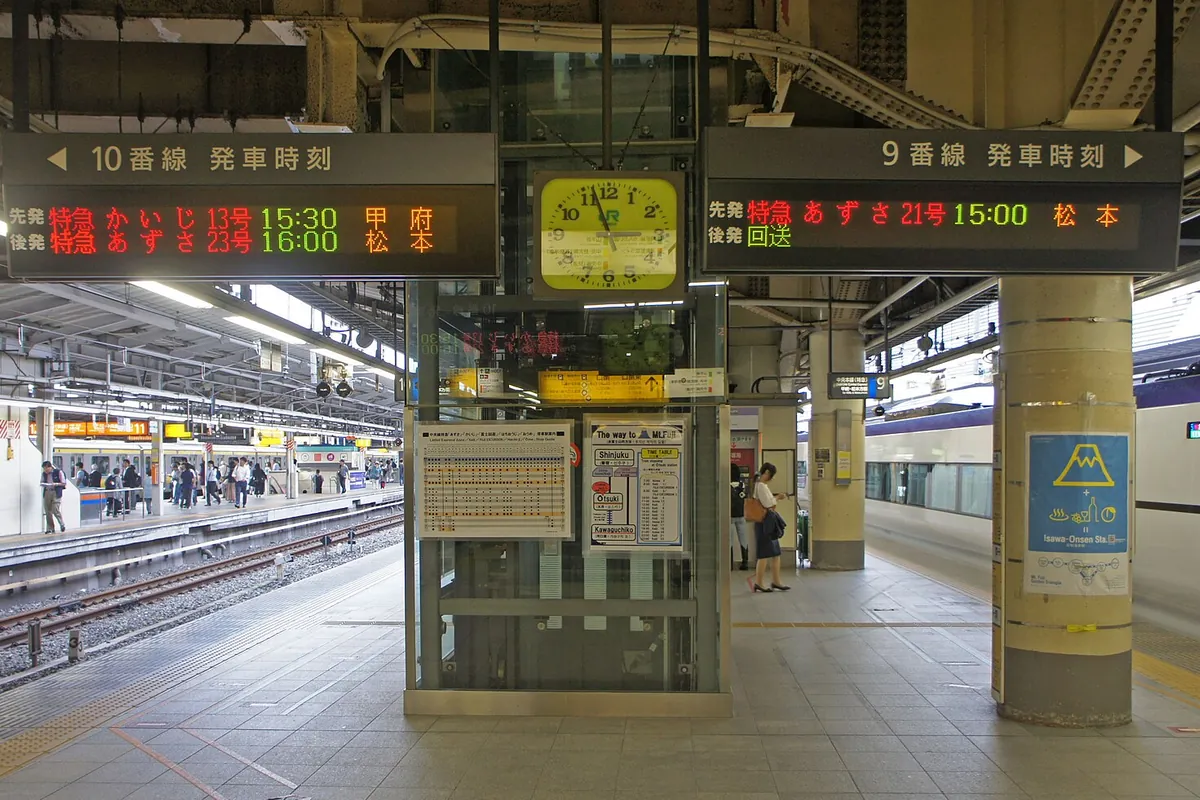 新宿駅のホームで「9番線 発車時刻」「10番線 発車時刻」の電光掲示板に特急あずさなどの案内が表示されている写真