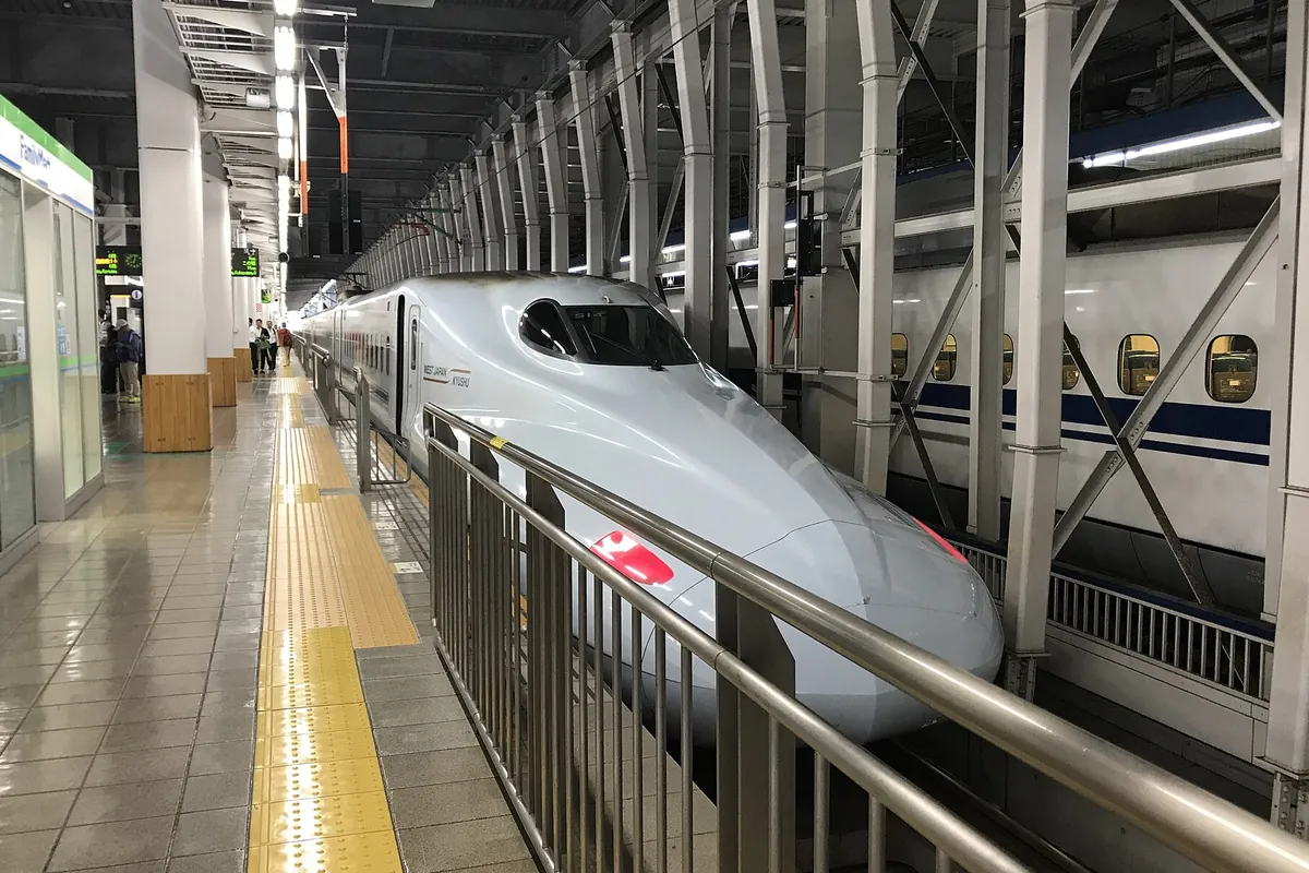 屋内の新幹線ホームに停車中の白い新幹線車両の先頭部分が大きく写る写真