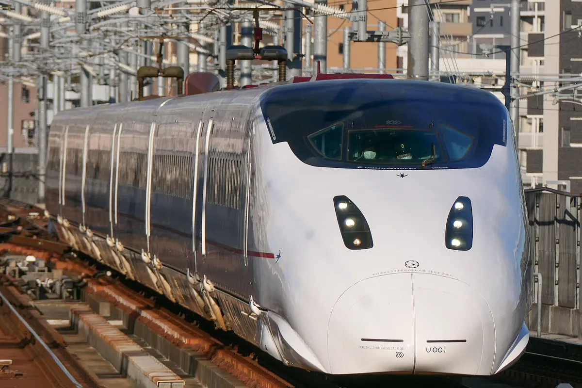 「KYUSHU SHINKANSEN 800」と車体に表示された白い新幹線車両が高架線を走行する先頭部分の写真。
