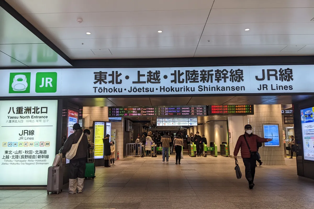 駅構内の改札前に掲げられた「東北・上越・北陸新幹線 JR線」の大きな案内看板と発車標の写真