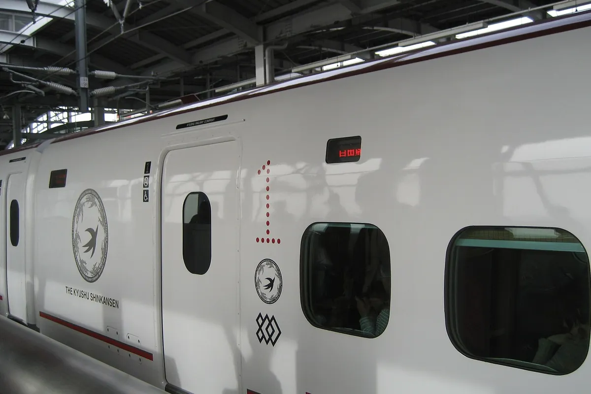 「THE KYUSHU SHINKANSEN」のロゴが入った九州新幹線の車両を駅のホームで横から写した写真