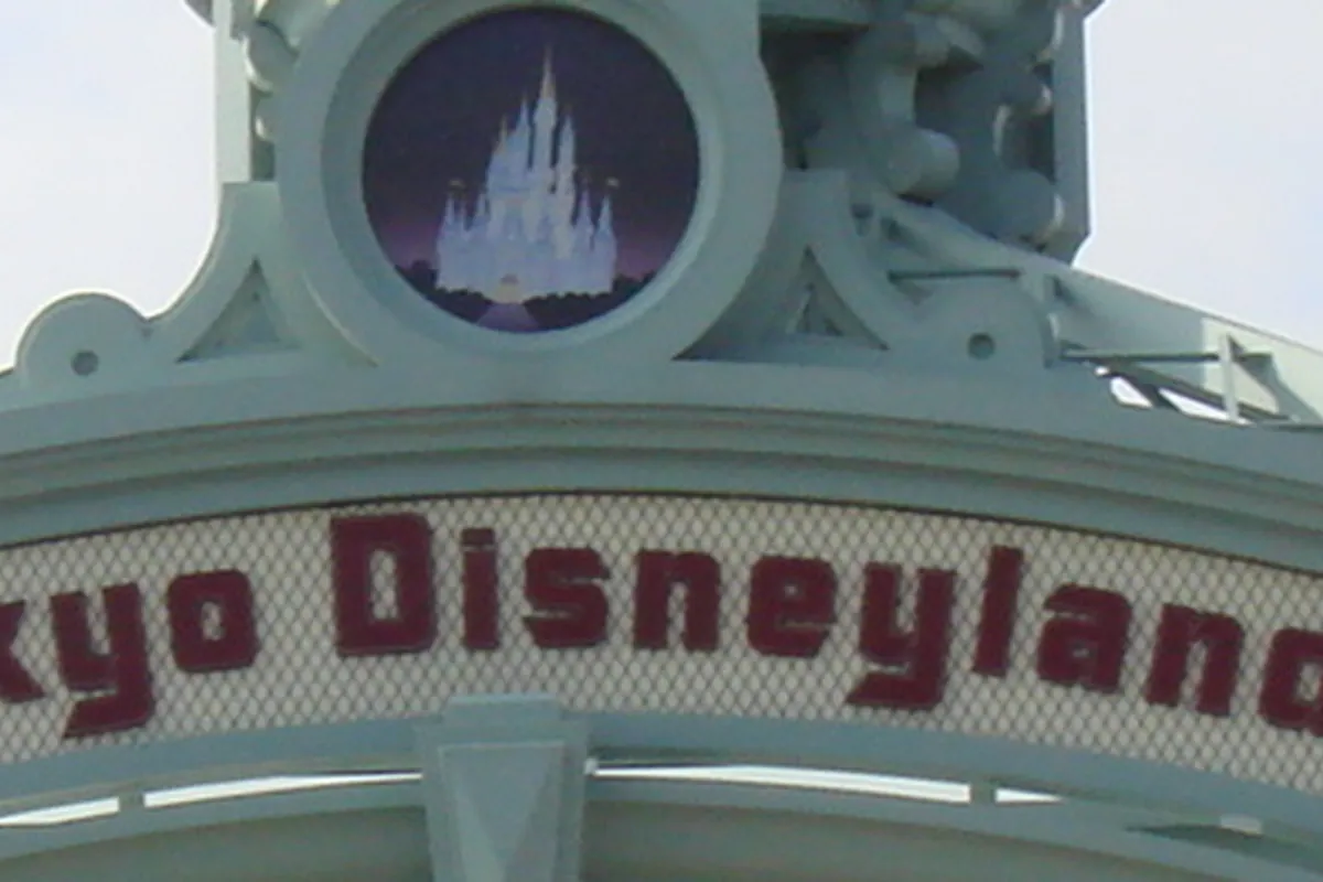 東京ディズニーランドのエントランス看板に「Tokyo Disneyland」の文字とシンデレラ城のロゴが掲げられている写真