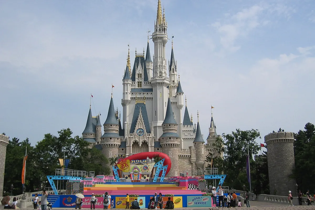 東京ディズニーランドのシンデレラ城の前に装飾されたステージが設けられ、見学する人たちがいる写真