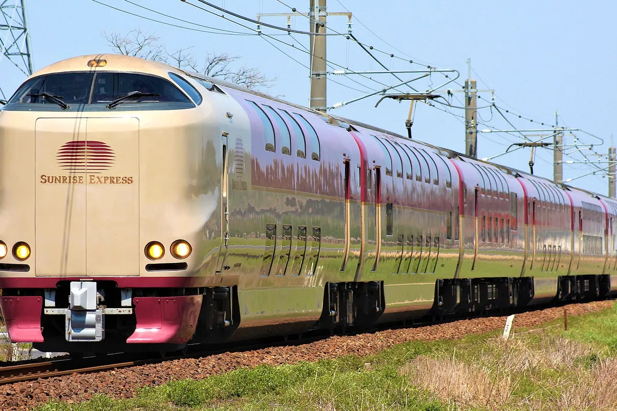 「SUNRISE EXPRESS」のロゴが入ったクリーム色と赤色の285系電車が線路上を走る様子の写真